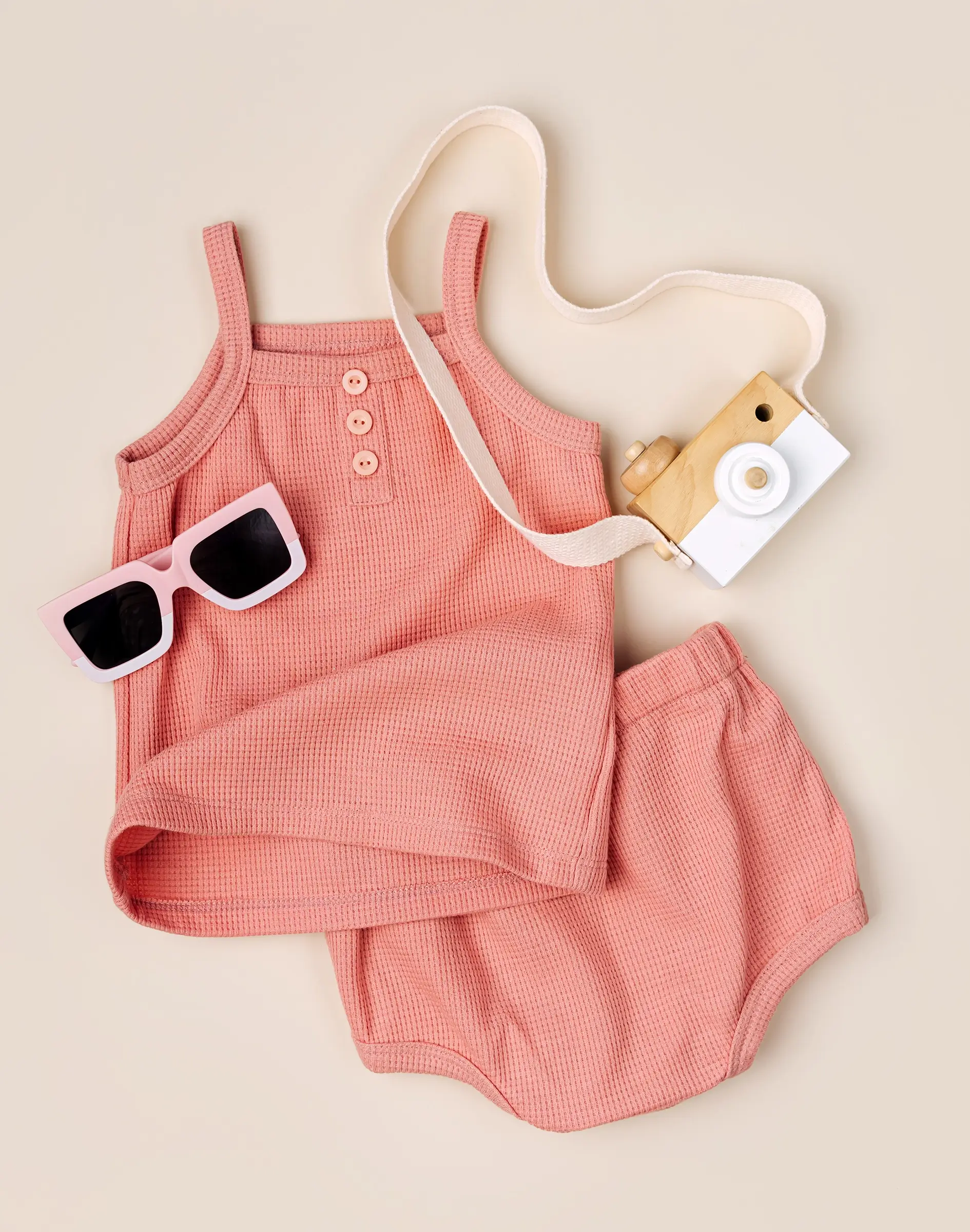 Stilvolles rosa Babyhemd mit rosa Höschen und Sonnenbrille. Babykleidung und Accessoires aus Baumwolle für den Sommer